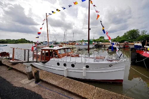 A white boat with flags moored at the dock in Woodbridge.
