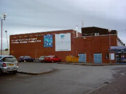 Edificio de ladrillo con señales y coches aparcados delante.