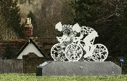 Sculpture of two cyclists with oak leaves on their torsos and wheels at Pixham End roundabout.