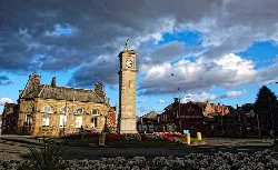 Torre del reloj con edificios históricos y macizo de flores en Goole.