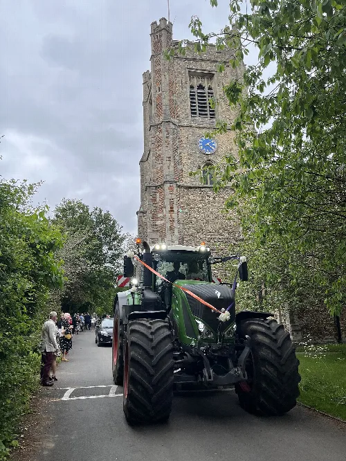 Torre de la iglesia con reloj y tractor en la calle delante.