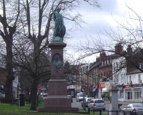 Bronze statue of Queen Victoria on a tall pedestal in Esher.
