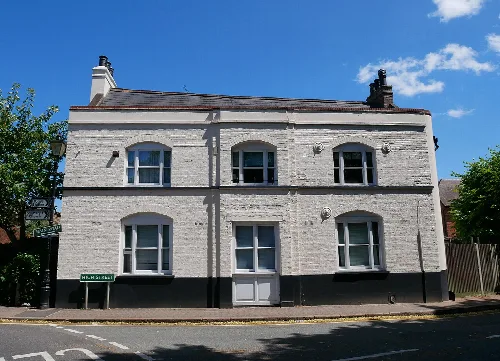 Edificio de dos pisos pintado de blanco con seis ventanas en una esquina en St Mary Cray.