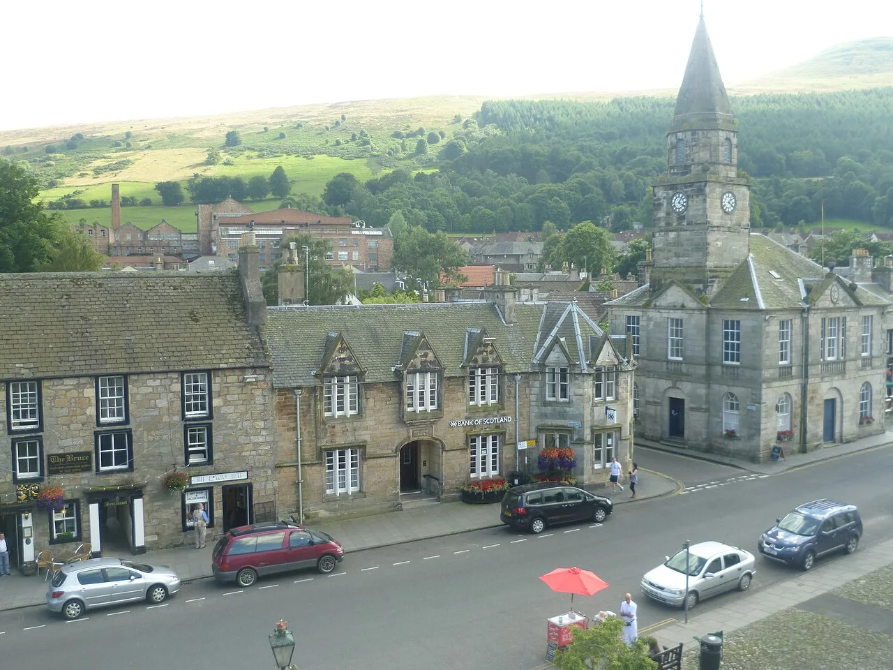 Street scene in Falkland with stone buildings and a church tower.