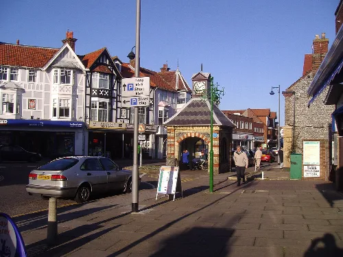 View of Sheringham town centre with shops, pedestrians, and a clock tower.