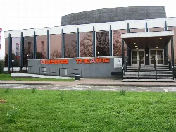 Modern theatre building with large glass windows and stairs at the entrance.