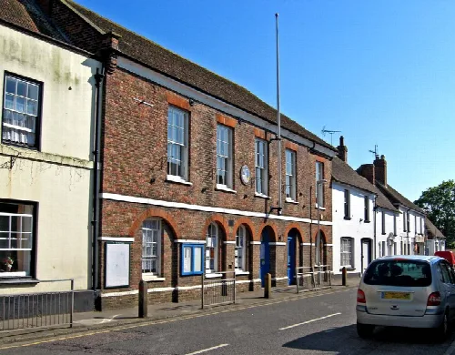 Brick building with arched windows and a blue door on High Street in Lydd.