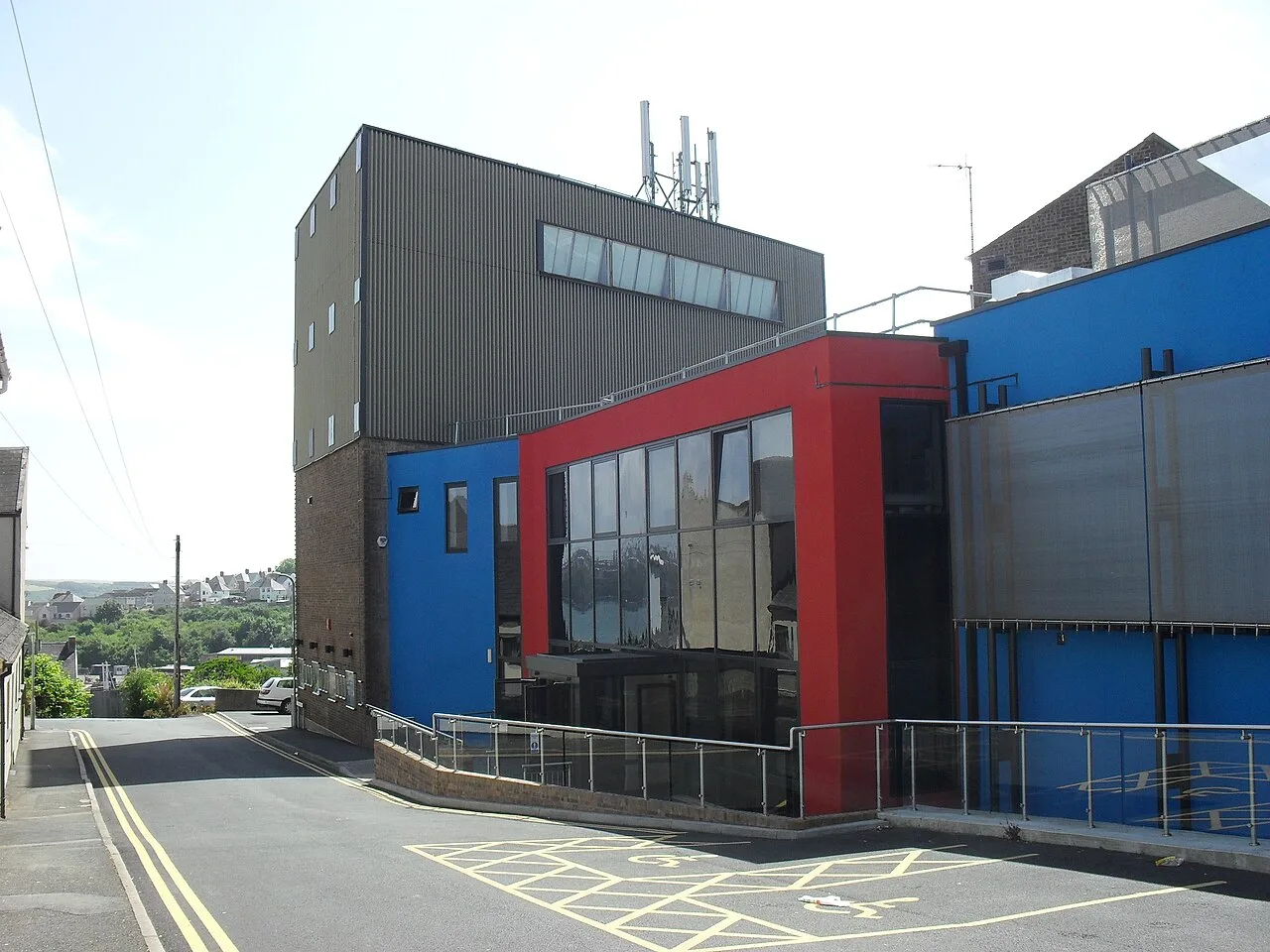 Edificio de teatro moderno con paneles rojos y azules en Milford Haven.