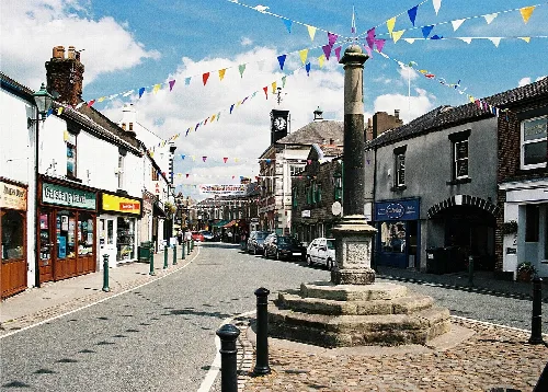 Marktkreuz im Garstang mit buntem Girlanden und Geschäften.