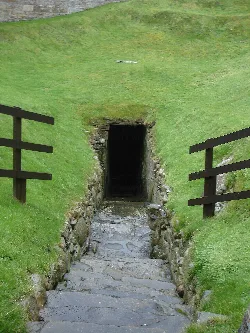 Stone steps and wooden railings leading to a dark well entrance in Burghead.