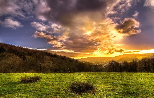 Atardecer sobre campos verdes y colinas lejanas en Risca.