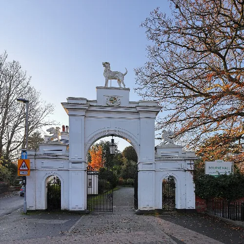White entrance arch with dog statues and a gate in Ewell, Surrey.