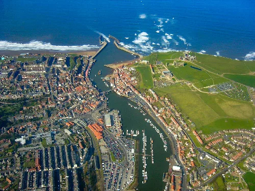Vista aérea de Whitby con puerto, ciudad y campos verdes.