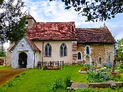 Stone and brick church with graveyard and trees.