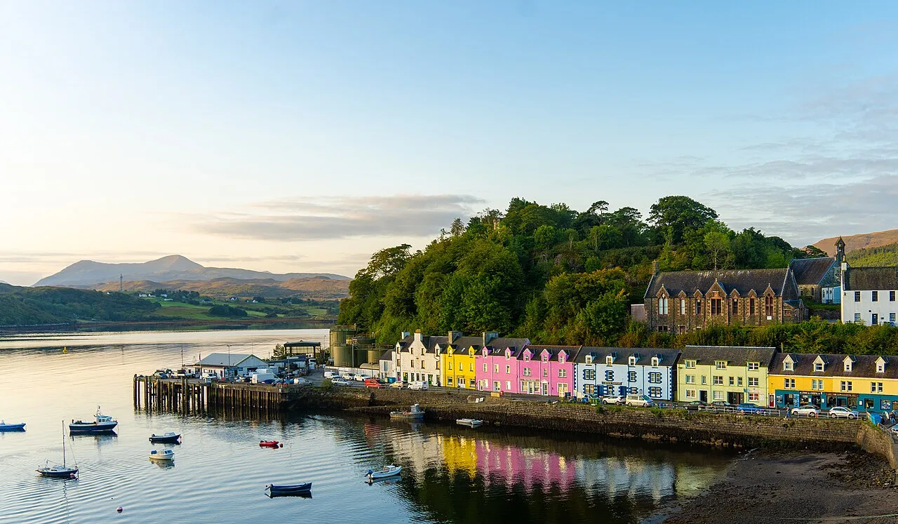 Casas coloridas en el puerto de Portree con colinas y barcos.