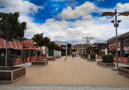 Breiter Fußgängerweg mit Geschäften, Bäumen und modernen Straßenlaternen im West Gate Leisure Park, Aldershot.