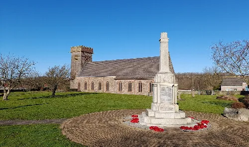 Gedenkstein in Harrington mit Kirche und Bäumen im Hintergrund.