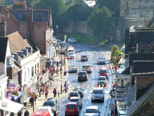 View of Battle High Street with shops, pedestrians, and parked cars.