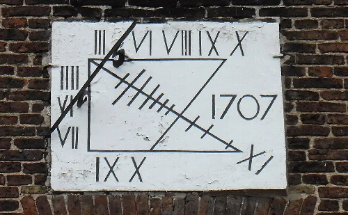 Eine Steinsonnenuhr mit römischen Ziffern und dem Jahr 1707 an einer Ziegelmauer.