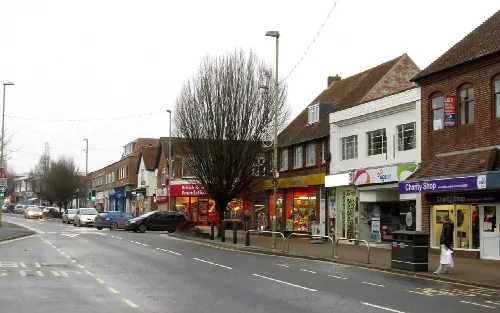 Street view of Broadway in Didcot with shops and parked cars.