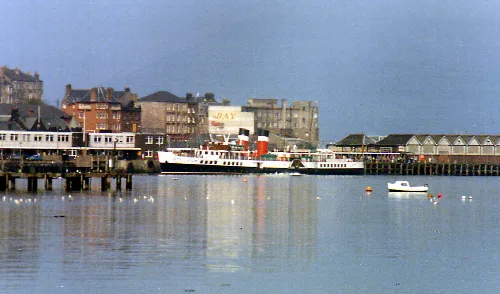 Steamship PS Waverley at Gourock pier with buildings and railway station canopies behind.