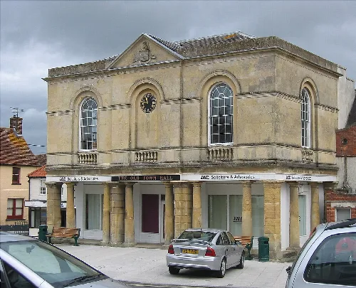 Edificio de piedra con ventanas arqueadas, reloj y columnas en Westbury.