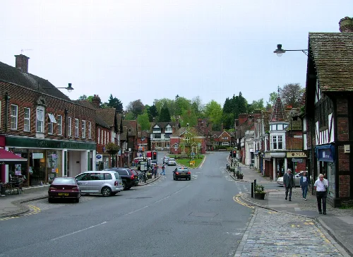 Street scene in Haslemere with shops, parked cars, and pedestrians.