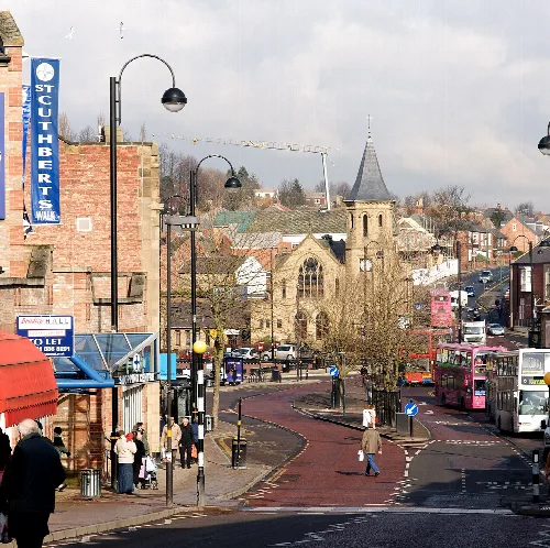 Street scene with shops, pedestrians, and a church in Chester-le-Street.