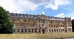 Un gran edificio histórico con fachada simétrica y muchas ventanas en Camberley.