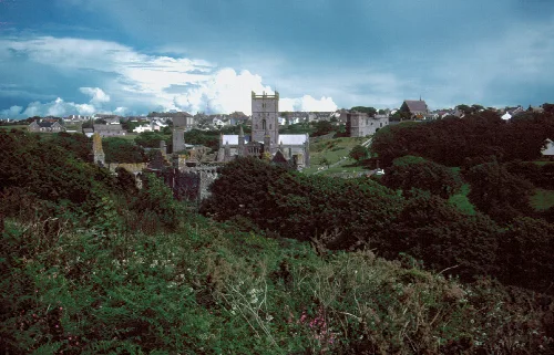 Pueblo con una catedral en una colina, rodeado de vegetación en Pembrokeshire, Gales del Sur.