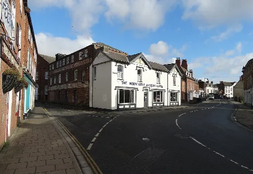 Un edificio blanco con señalización negra en una esquina de la calle en Horncastle.
