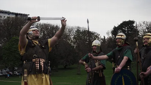 Soldados romanos en disfraz saludan con armas y escudos en Callendar House.