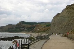 Acantilados y paseo en West Bay, Dorset, con personas caminando y sentadas.