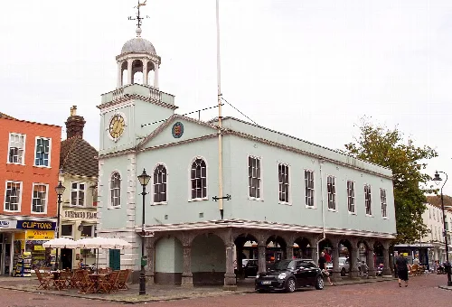 A historic market building with a clock tower and arched ground floor in Faversham.